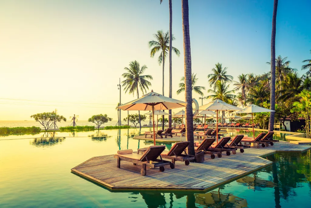 An exclusive, low-density private villa infinity pool overlooking a secluded ocean cove during sunset